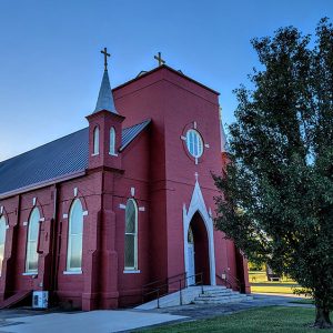 Multistory red brick church building with spires and tree