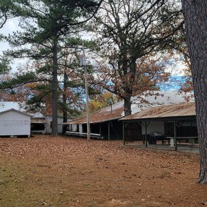 Collection of single-story wooden buildings with pavilion among trees