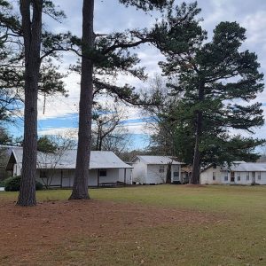 row of single story white cabin-type buildings and trees