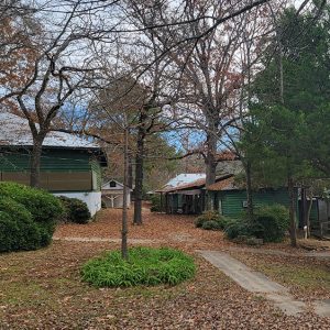 Green metal buildings on hillside with trees