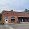 Orange brick storefront building next to two other storefronts with awnings