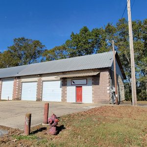 Tan brick building with five garage doors and a red entrance door