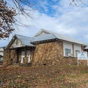 Single story rock house building with covered entrance and window air conditioning unit