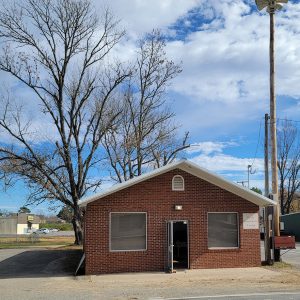 Single story red brick building with two windows in front