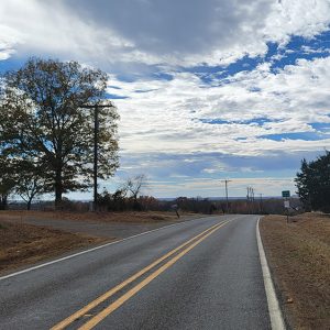 Cresting hill on country highway with farm and pond on one side