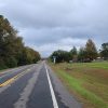 straight highway with trees on one side and a few cars and businesses on the other