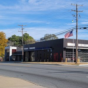 Black metal rectangular fire department building with multiple glass bay doors