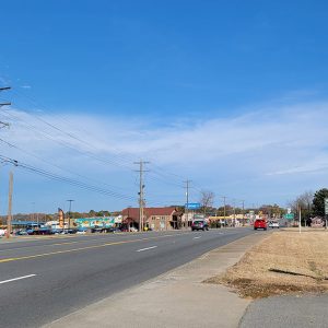 Small town street scene with multiple fast food restaurants and other buildings on both sides of four-lane highway