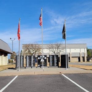 Semicircle of five black granite memorial stones with flagpoles and parking lot