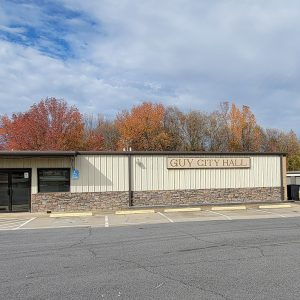 Single story rock and metal city hall building with parking lot