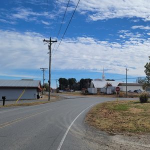 Rural road curving amid church and business buildings