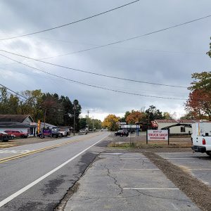 Small town street with businesses and parked cars on both sides