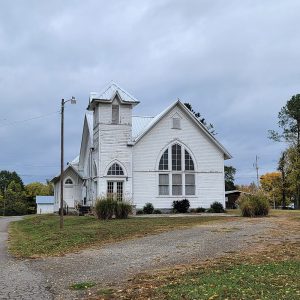 Multistory white wooden church building with peeling paint and bell tower