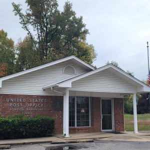 Single story orange brick post office building with covered entrance