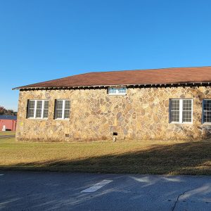 Single story stone building with concrete block building attached