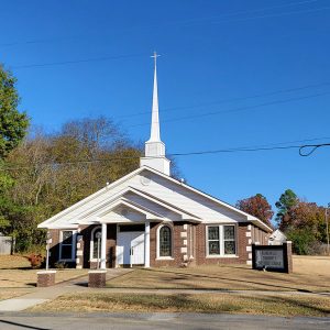 red brick and white church building with steeple and covered entrance