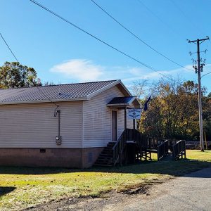 Single story beige wooden building with Masonic emblem