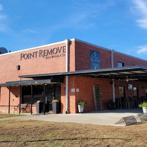 Multistory red brick brewing company with covered entrance and covered porch with tables