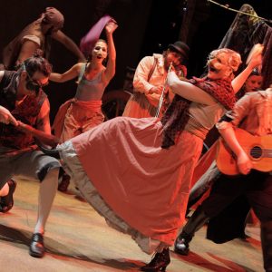 Group of masked actors on stage dancing