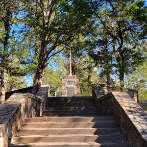 Metal sign and flagpole on stone plynth and steep staircase leading up to it