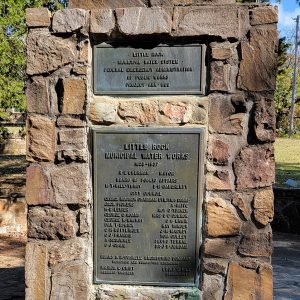 Metal sign saying "Little Rock Municipal Water System Federal Emergency Administration of Public Works Project Ark 1106"