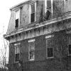 Multistory brick building in disrepair with vines growing up the side