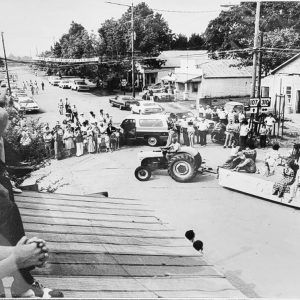 view from above of parade with tractor-drawn float and spectators