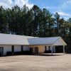 Single story white brick church building with covered entrance and parking lot