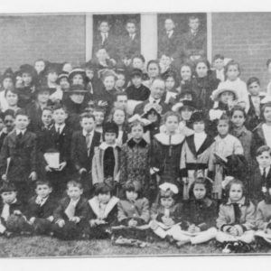 Group of young white boys and girls in formal dress posing by building