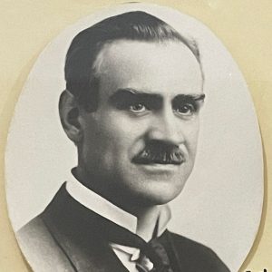 White man with mustache in suit and tie