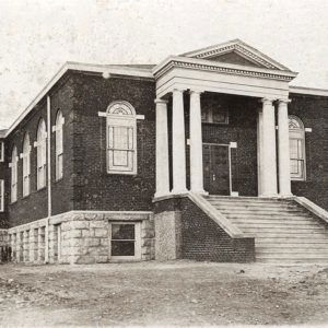 Multistory brick and stone church building with steps leading up to front entrance