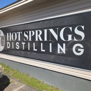 wide black sign saying "Hot Springs Distilling"