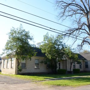 Single story tan brick building with trees