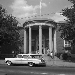 two people walking down the steps of marble post office building with Greek columns