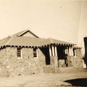 Single story rock school building with covered entrances