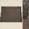 Plaque about a grave and a grave inside a fence