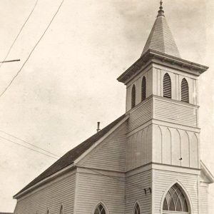 Multistory white wooden church building with bell tower