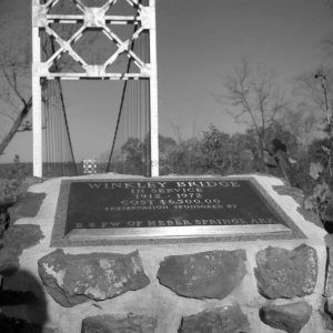 Sign embedded in stone and concrete in front of a bridge