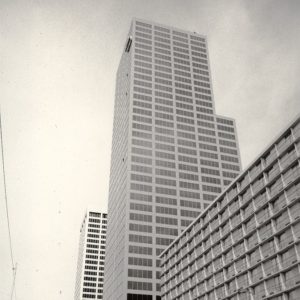 View of a skyscraper among other city buildings and cars