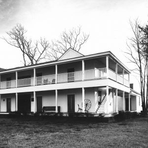 Multistory white wooden house with wrap-around second story porch