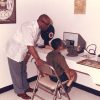 African American man giving African American boy an eye exam at a machine