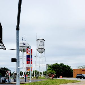 Water tower with town name on it next to another water tower