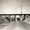 Bridge over a road with supports on either side and in the middle of the road