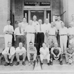 White men standing and sitting on steps of building