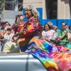 African American woman in flowing robe riding in a car in a parade