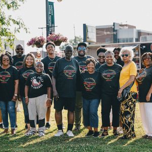 Group of African American men and women standing in a group in front of building and food truck