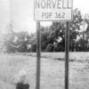 Young white girl standing beneath city sign.