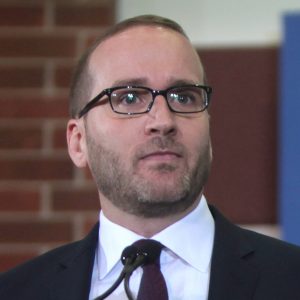 White man in a suit and tie with glasses