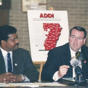 black man and white man in suits and ties at desk with microphones