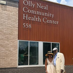 African American man and woman standing before brick and wooden building